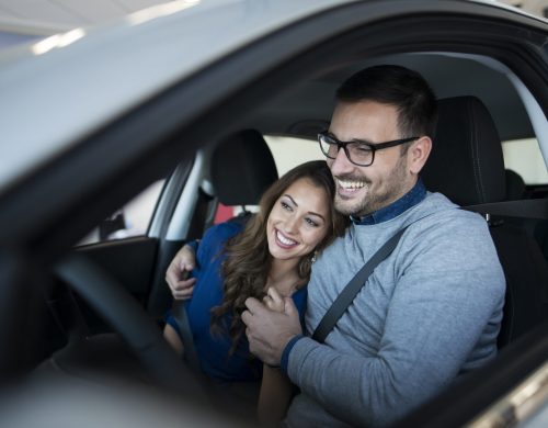Happy young couple enjoying their brand new car.
